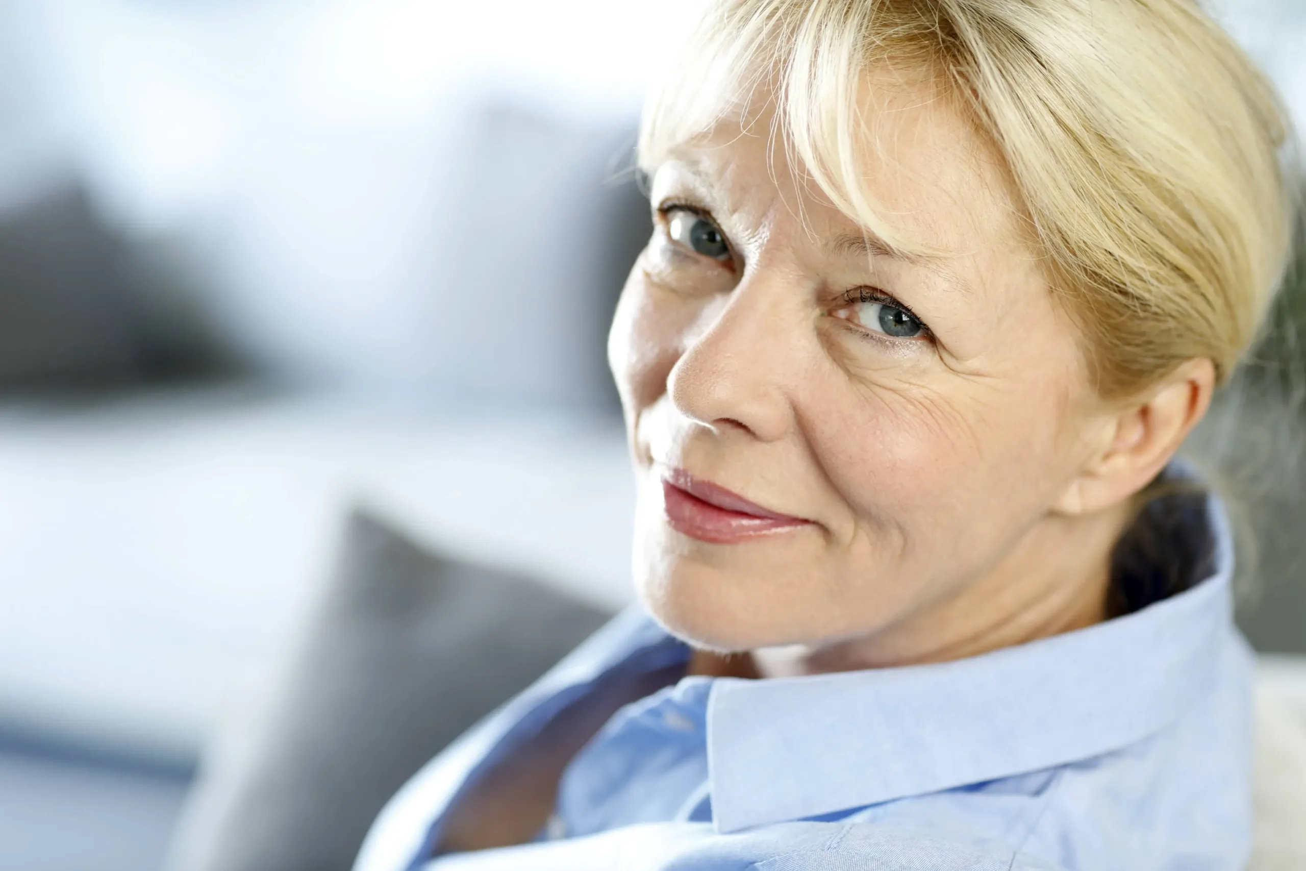 A woman in professional wear, looking at the camera with a cheerful smile