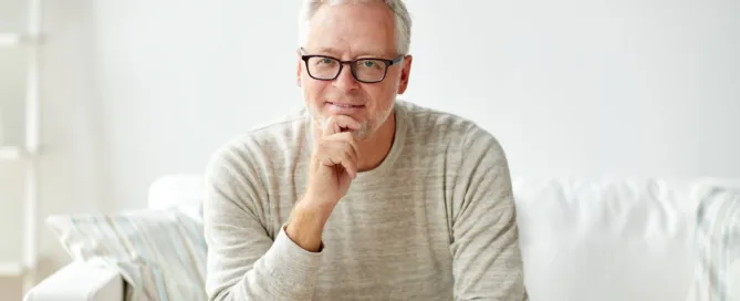 A man wearing glasses who ios smiling with a friendly expression, casually dressed